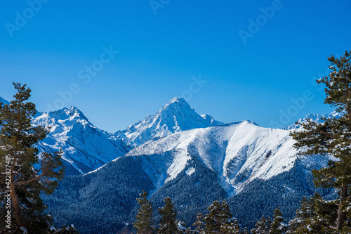 Snow covered Caucasus mountains in winter sunny day. View from ski slope. Arkhyz ski resort, Russia.