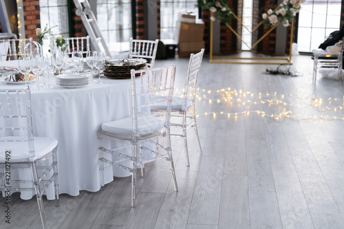 Transparent plastic chairs for wedding guests. Modern loft space, large windows.