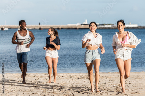 Diverse friends running on beach together