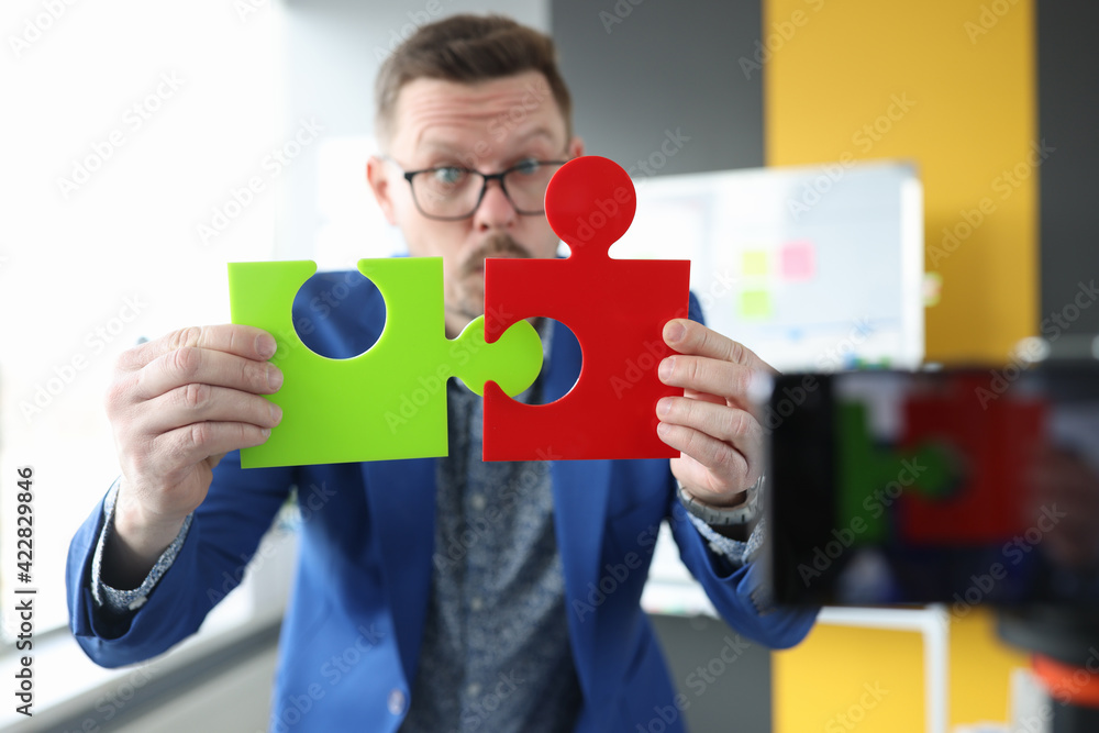 Male business blogger connects colorful puzzles closeup Male business blogger connects colorful puzzles closeup