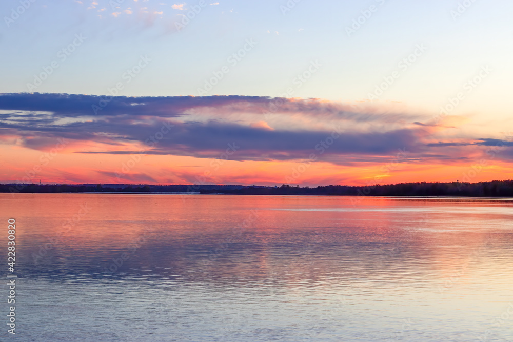 Panoramic view of a blue, pink and yellow sunset reflecting on the river