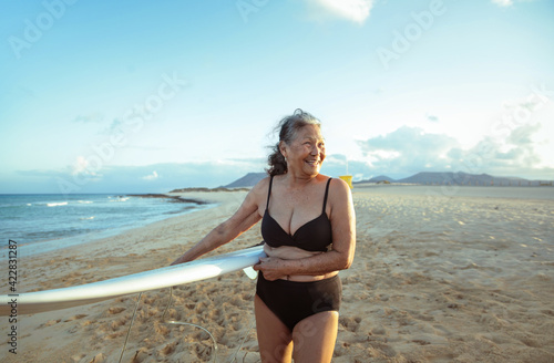 Photography Beautiful senior woman going to surf in the ocean - Mature filipino woman practi