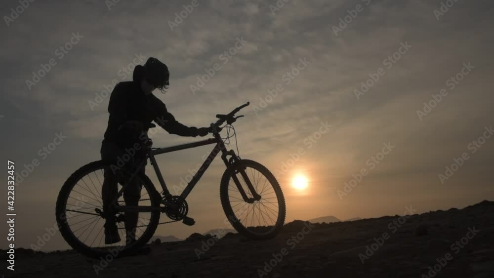 Stock video of a cyclist arriving on a mountain bike to watch the sunset, wearing case or sunglasses and a protective mask left to right at sunset. Copy space Stock video of a cyclist arriving on a mountain bike to watch the sunset, wearing case or sunglasses and a protective mask left to right at sunset. Copy space