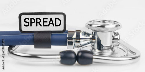 On the white surface lies a stethoscope with a plate with the inscription - SPREAD