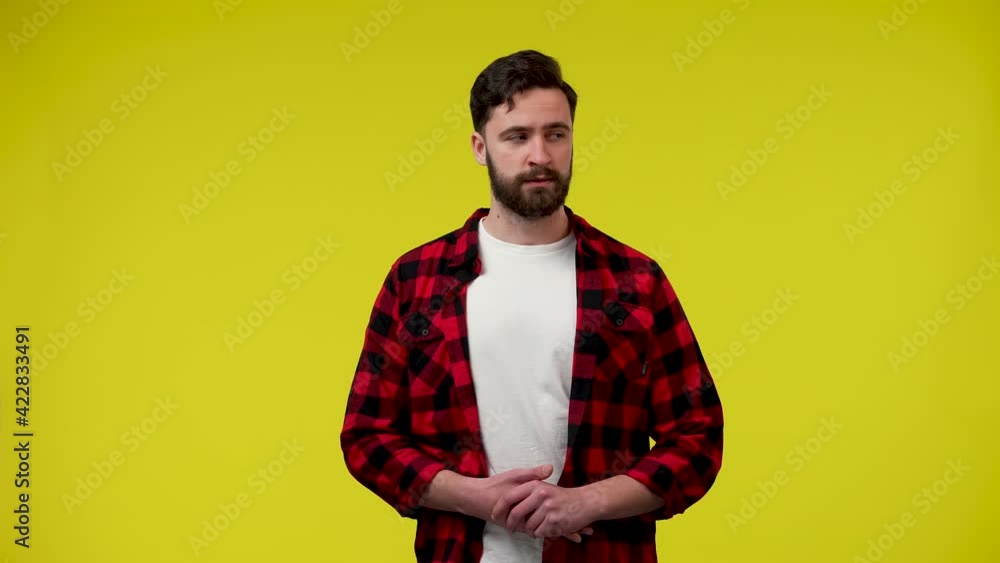 A man looks around, says something and shows a gesture of silence, puts a finger to his lips. Secret, gossip concept. A man on a yellow background in the studio. Close up. Slow motion ready 59.97fps. A man looks around, says something and shows a gesture of silence, puts a finger to his lips. Secret, gossip concept. A man on a yellow background in the studio. Close up. Slow motion ready 59.97fps.