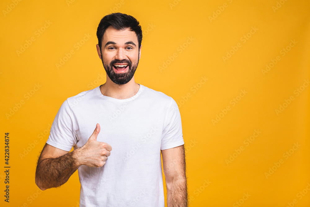 Happy young man. Portrait of handsome young man smiling while standing isolated over yellow background. Thumbs up. Happy young man. Portrait of handsome young man smiling while standing isolated over yellow background. Thumbs up.