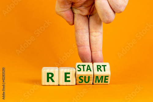 Restart and resume symbol. Businessman turns cubes and changes the word 'restart' to 'resume'. Beautiful orange background. Business and restart - resume concept. Copy space. photo