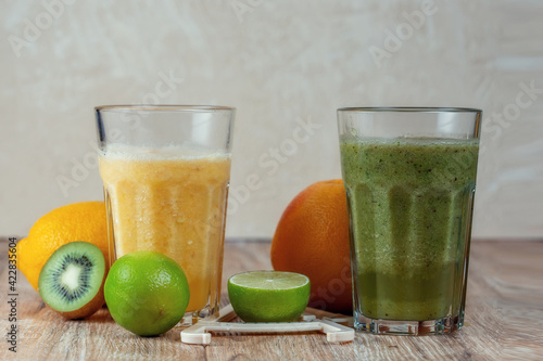 Tall glasses of kiwi and spinach smoothies in a row surrounded by fruits