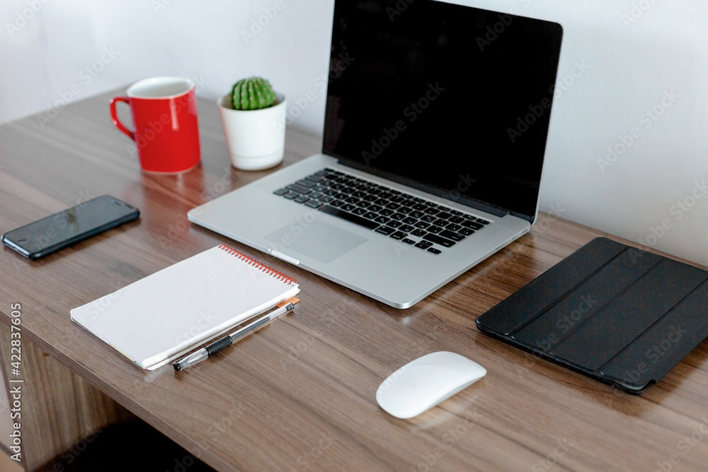 Office at home. Laptop, notebook, pen are on the table near the white wall. Office at home. Laptop, notebook, pen are on the table near the white wall.