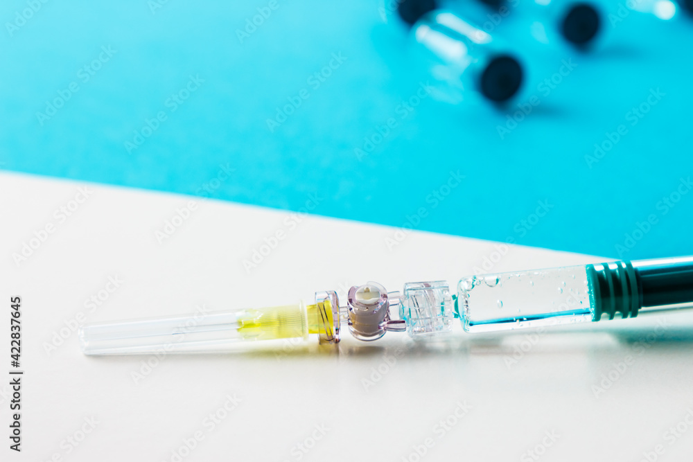 Syringe close up with several medical vials behind. Syringe close up with several medical vials behind.