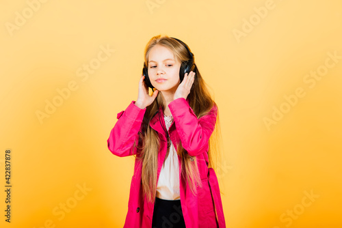 Photo of attractive girl using wireless headphones isolated over yellow background