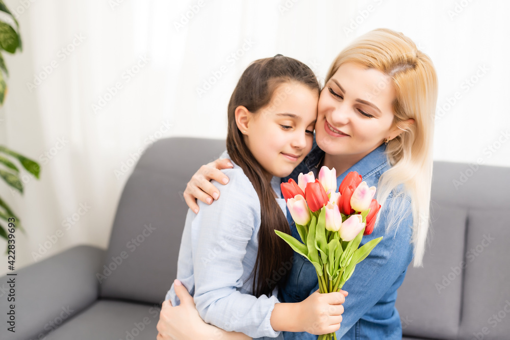 child daughter congratulates mother and gives a bouquet of flowers tulips child daughter congratulates mother and gives a bouquet of flowers tulips