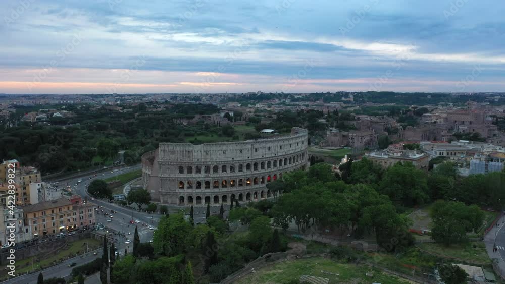 Aerial view of Colosseum, monument in Rome, Italy. Coliseum in Roma seen from drone flying in sky. Old roman building and urban landscape of Italian city with traffic and cars on the streets at sunset Aerial view of Colosseum, monument in Rome, Italy. Coliseum in Roma seen from drone flying in sky. Old roman building and urban landscape of Italian city with traffic and cars on the streets at sunset
