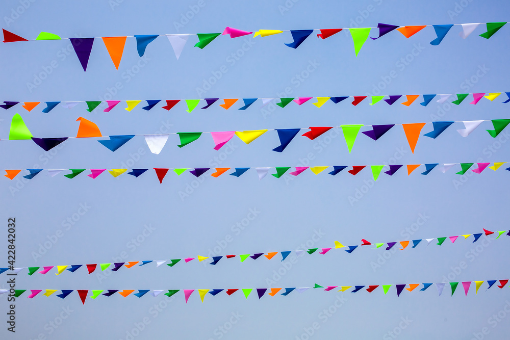 Obraz premium triangular festive multi-colored flags are suspended on a tight rope against the background of the sky, nobody.