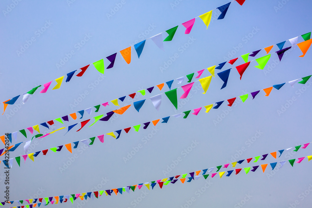 Obraz premium triangular holiday multi colored flags are suspended on a tight string outdoors park against the background of the sky, nobody.