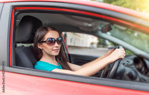 Happy beautiful woman is driving a car.