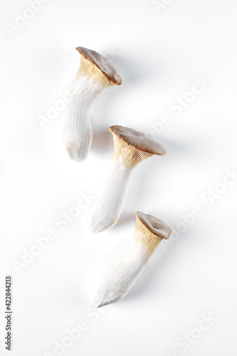 Collage of fresh whole and chopped eringi mushrooms isolated on white background. View from above