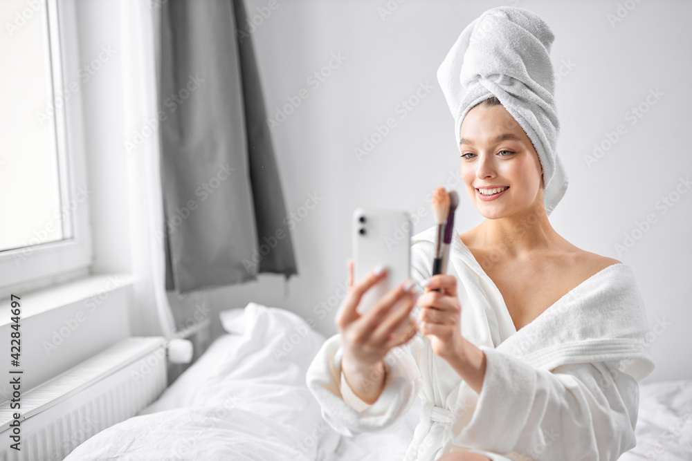 smiling female take photo on smartphone, holding make-up brushes smiling female take photo on smartphone, holding make-up brushes