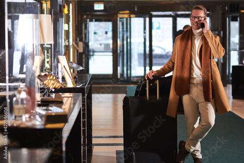 Businessman in coat goes to reception, arrived in hotel