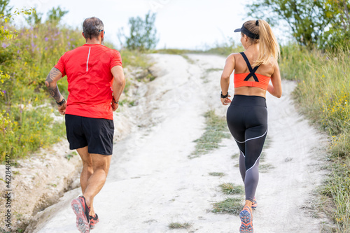 Back view of couple or friends running outdoors