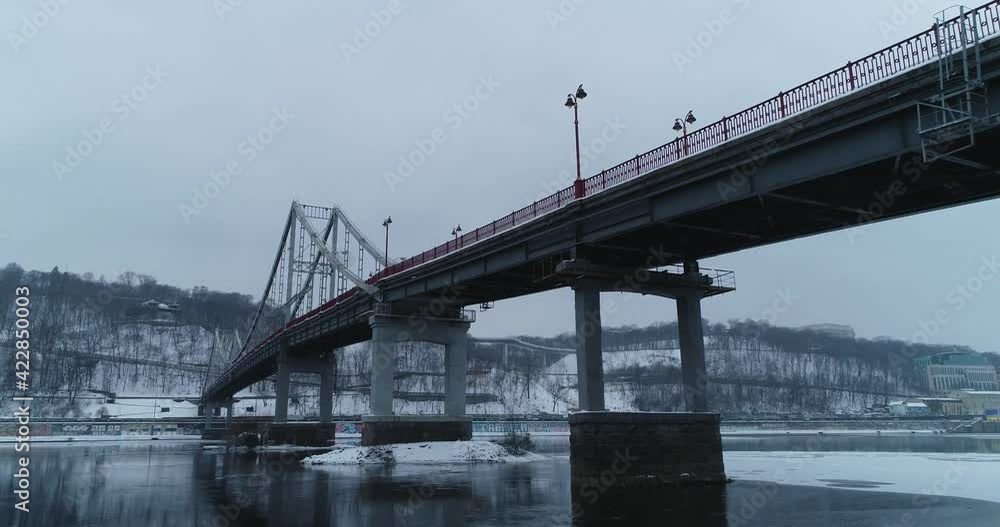Kyiv. Ukraine. Aerial. Winter. Park pedestrian bridge over the Dnieper River, which connects the central part of Kiev with the park area and the beaches of Trukhaniv Island. Frozen. Kyiv. Ukraine. Aerial. Winter. Park pedestrian bridge over the Dnieper River, which connects the central part of Kiev with the park area and the beaches of Trukhaniv Island. Frozen.