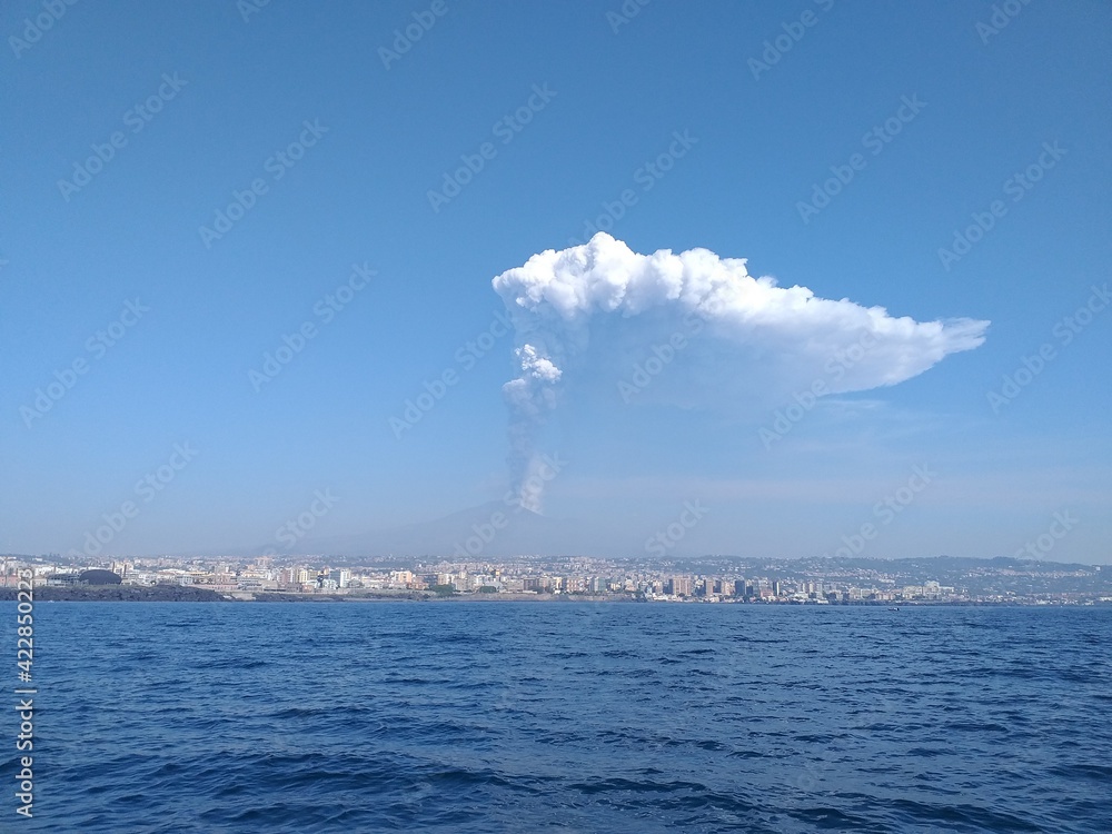 Parossismo del vulcano etna nell'anno 2021 con altissima colonna di cenere e lapilli, vista dal mare con la città di Catania alle pendici