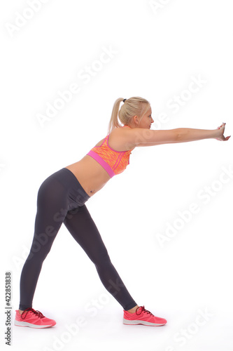 While exercising  the girl stands straddling and stretches out both hands in front of her. Front view