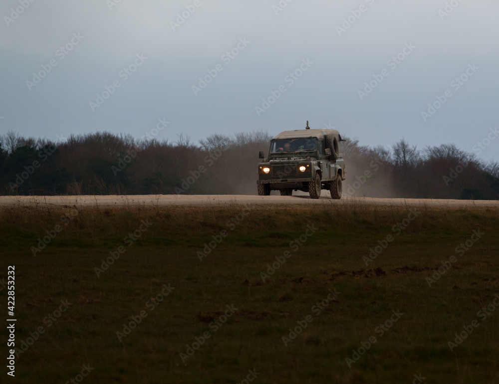Fototapeta premium british army land rover defender 4x4 speeds along a dusty stone track 
