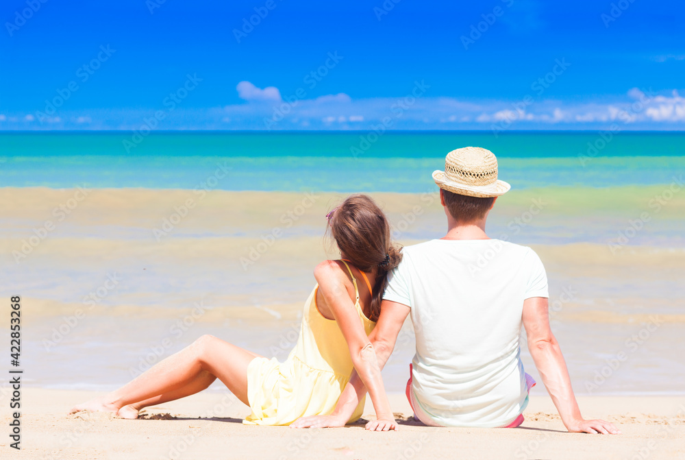 back view of couple sitting on a tropical beach on Maldives