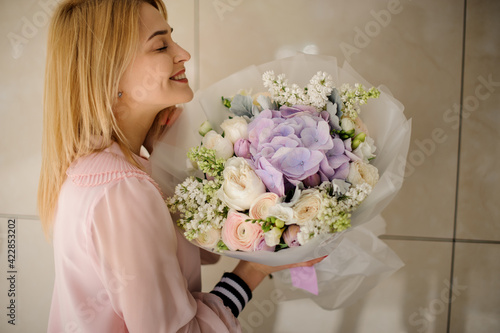 view of happy blonde woman with delicate floral bouquet in her hands