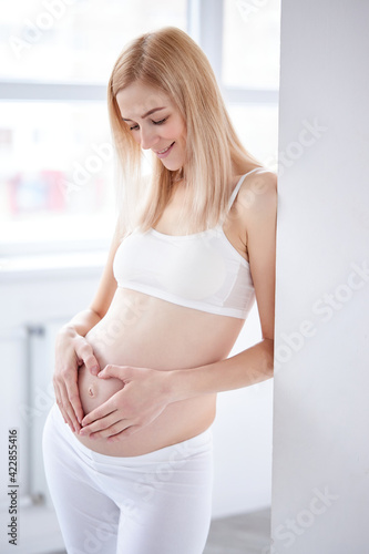 pretty pregnant woman posing, making heart shape from hands on belly Free Download pretty pregnant woman posing, making heart shape from hands on belly - GFXLoad