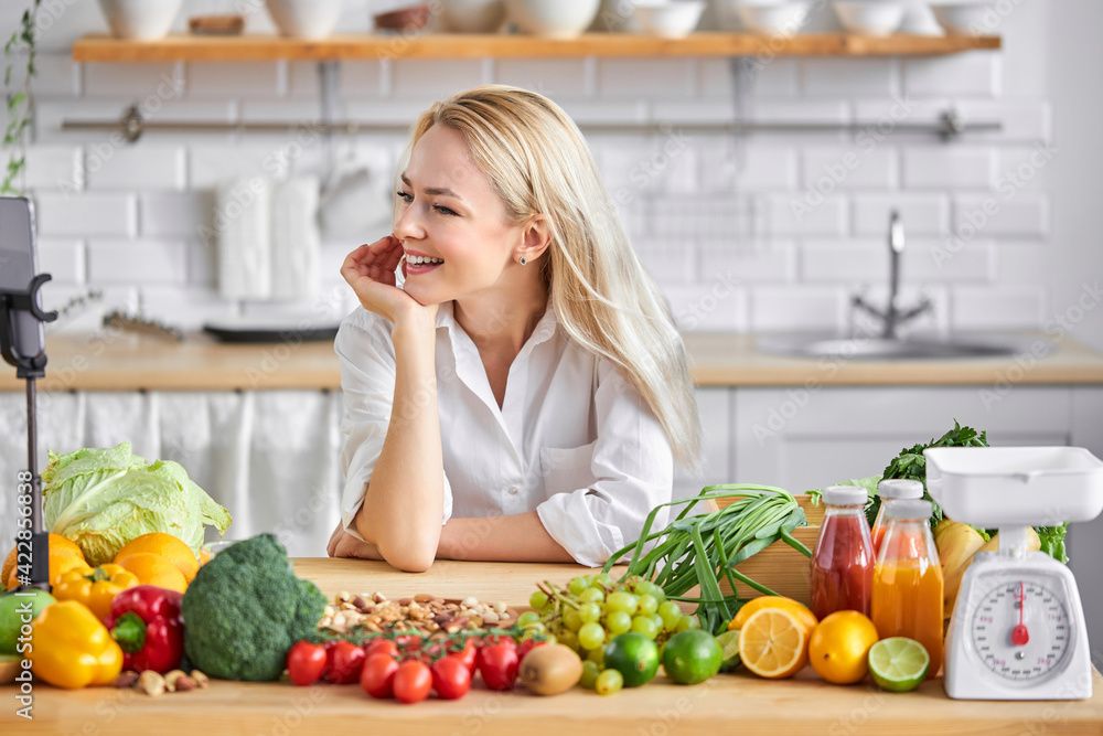 blonde pleasant woman of european appearance like healthy eating, stand by table with fresh food blonde pleasant woman of european appearance like healthy eating, stand by table with fresh food