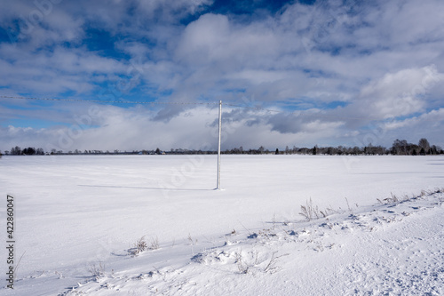 Latvian Rural landscape with a lot of white fluffy snow where you can see an electric pole in the middle that has snowed