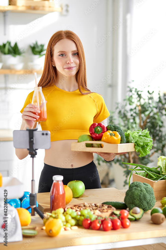 Friendly redhead woman holding natural detox juice in hands