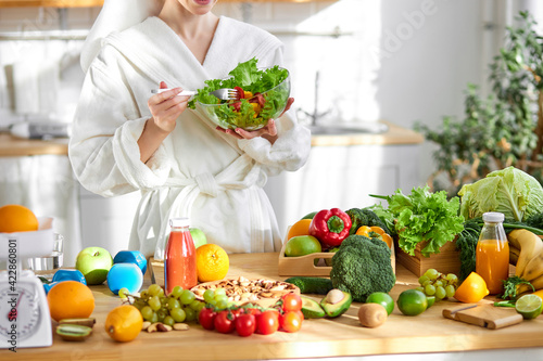 unrecognizable female in bathrobe enjoy making and eating fresh salad from vegetables