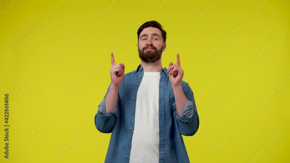 A man looks at the ad slot at the top of the screen and points with two forefingers, then shows a thumb up with both hands. A man on a yellow background. Close up. Slow motion ready 59.97fps. A man looks at the ad slot at the top of the screen and points with two forefingers, then shows a thumb up with both hands. A man on a yellow background. Close up. Slow motion ready 59.97fps.