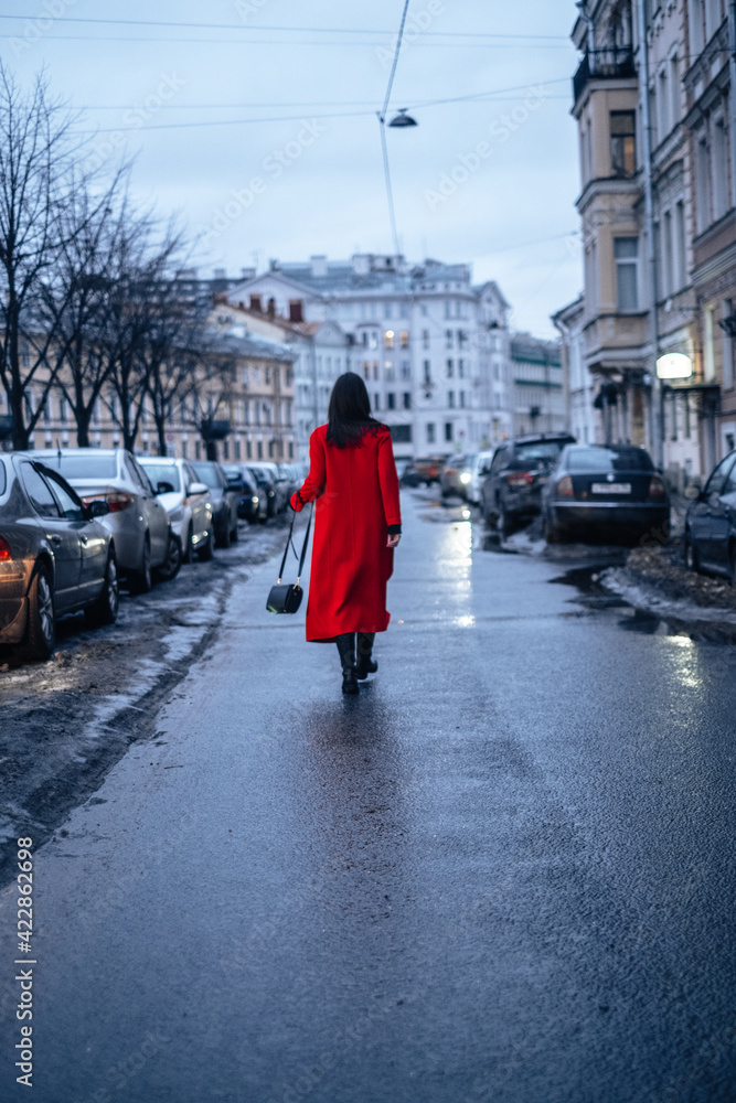 a girl in a red coat walks down the street