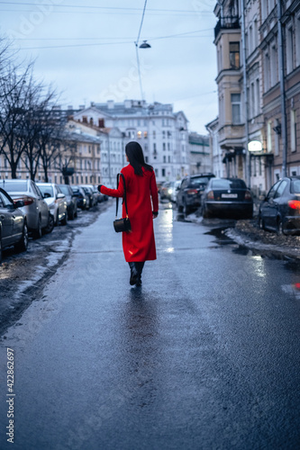 a girl in a red coat walks down the street