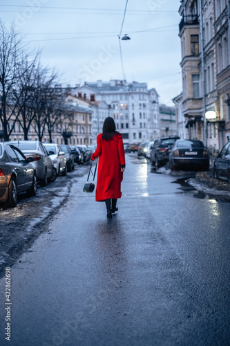 a girl in a red coat walks down the street