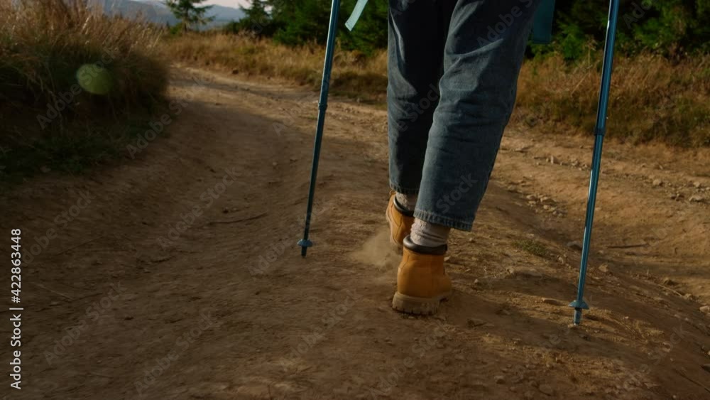 Tourist in hiking boots walking on dirt road. Woman trekking in mountains Tourist in hiking boots walking on dirt road. Woman trekking in mountains