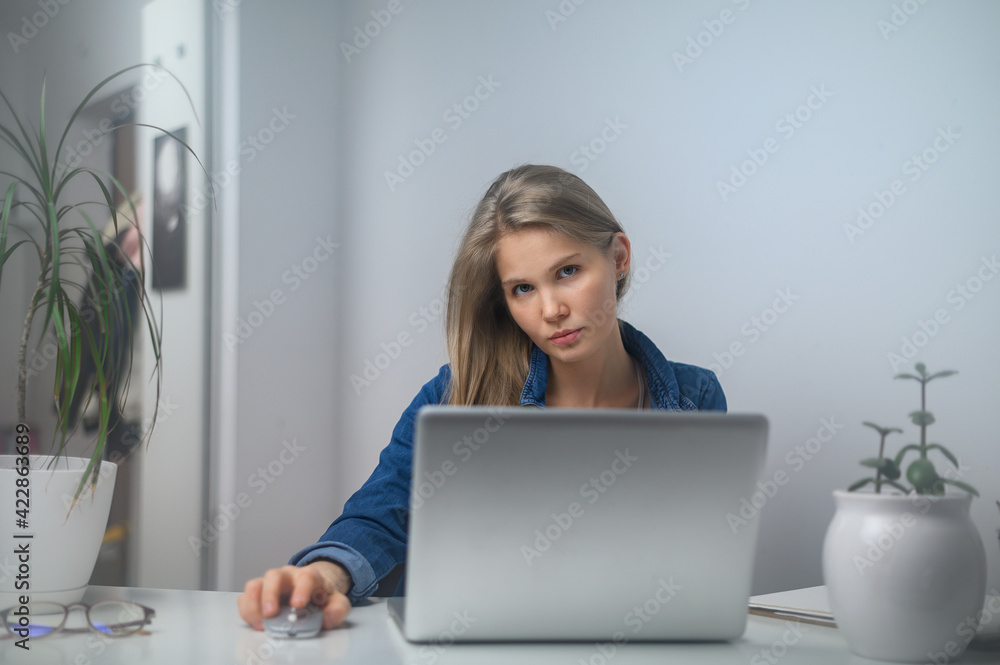 A girl with a laptop is studying at an online school. White room background A girl with a laptop is studying at an online school. White room background