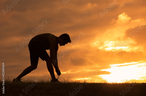Male runner tying his shoes before run. Fitness and exercise concept. 