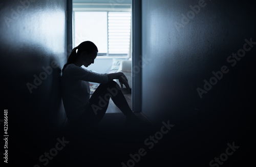 Exhausted, tired and sad woman sitting on bedroom floor