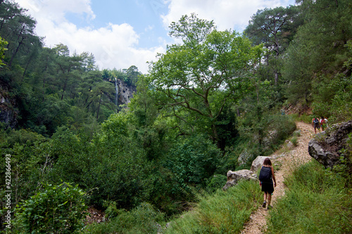 The hikers with backpacks walking on a narrow trail