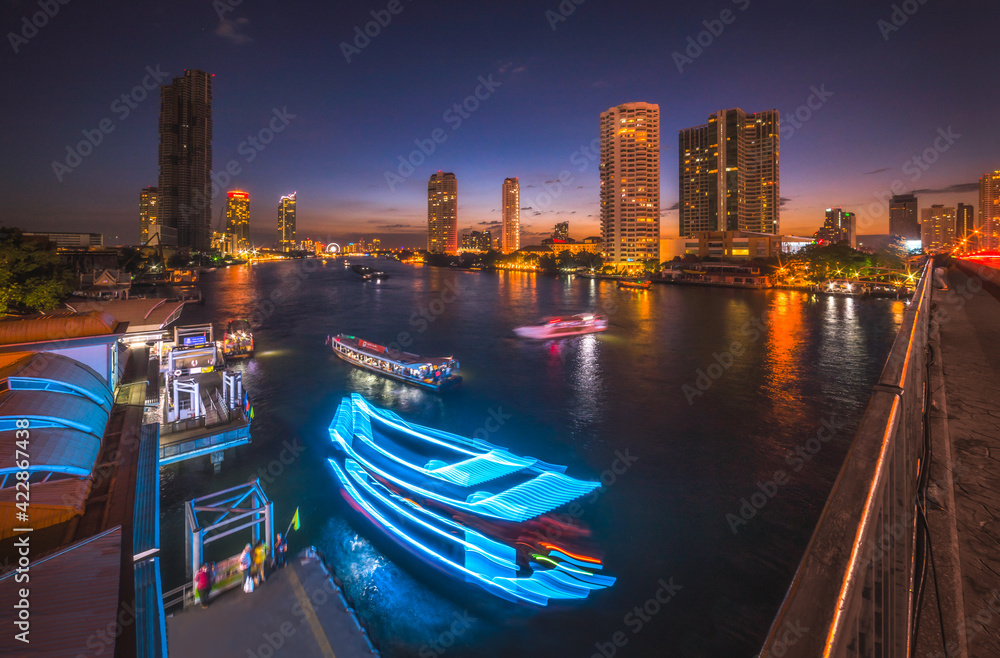 Skyscrapers and Light Trails of Traffic on the Chao Phraya River in Bangkok, Thailand as Seen from Taksin Bridge at Might
