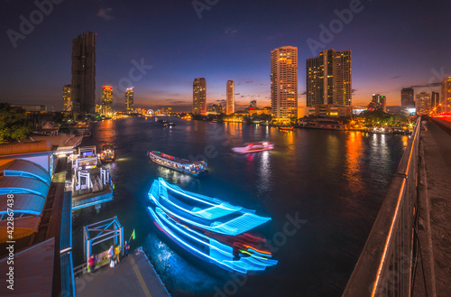 Skyscrapers and Light Trails of Traffic on the Chao Phraya River in Bangkok  Thailand as Seen from Taksin Bridge at Might