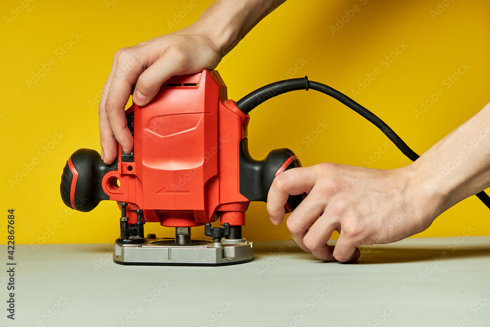 Fototapeta premium unrecognizable male turning on Electric fret saw isolated on yellow background