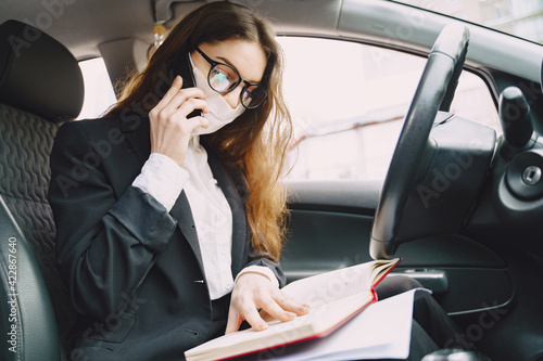 Businesswoman in a black mask sitting inside a car © prostooleh