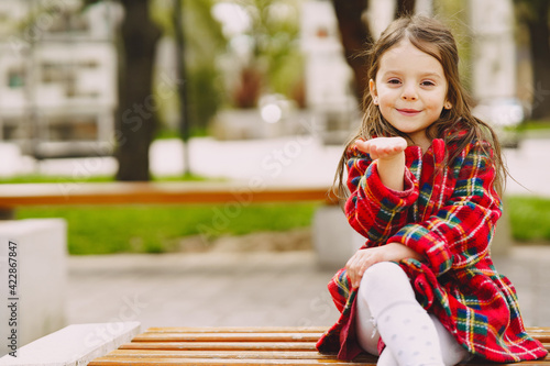 Little girl in a park sitting on a bench