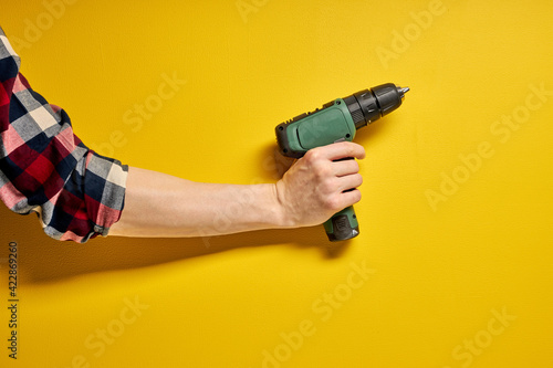 electric cordless screwdriver drill isolated on yellow background, professional home repair tool